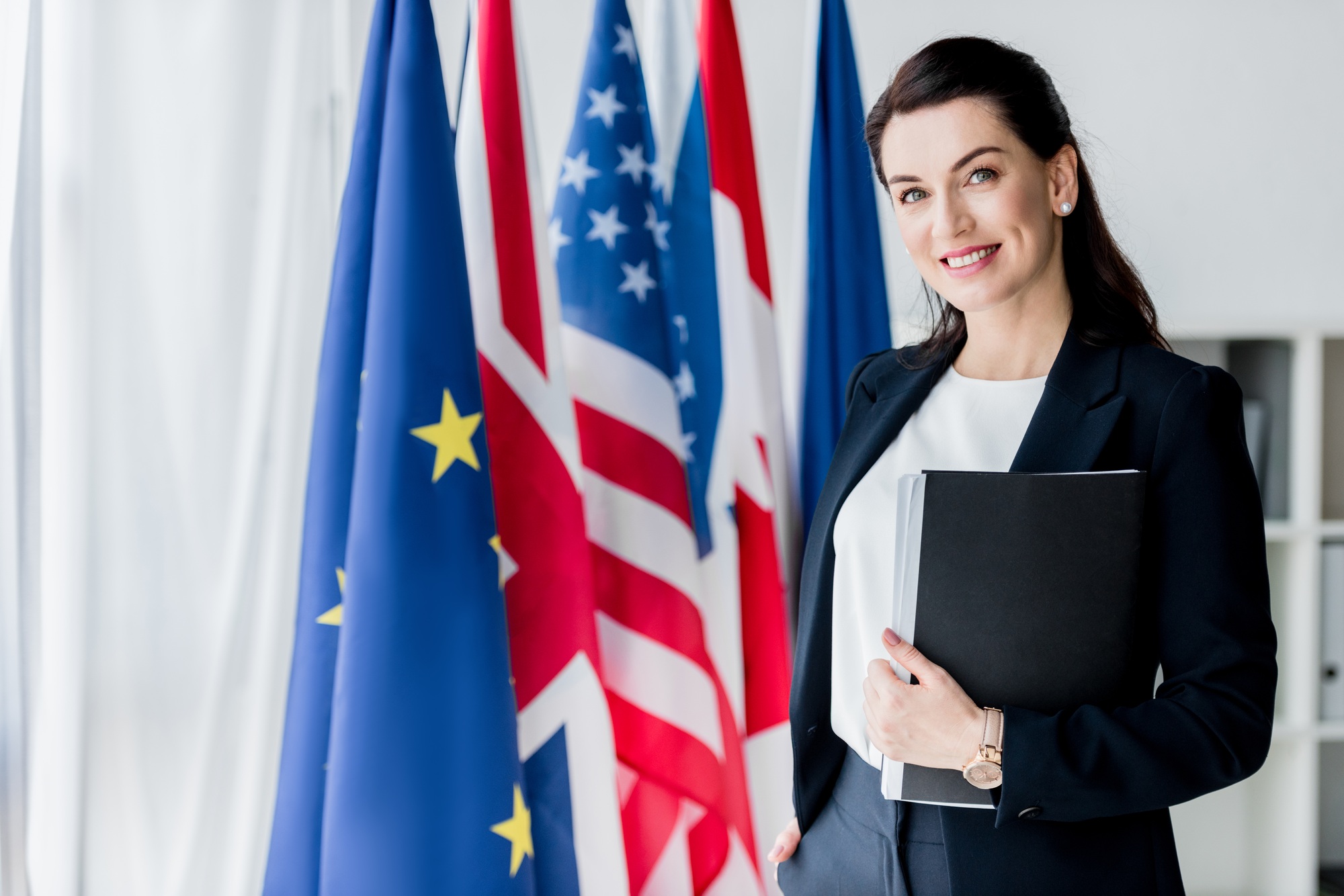 smiling ambassador looking at camera near flags